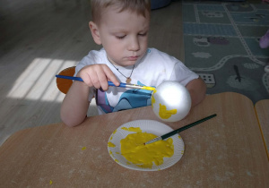 Chłopiec koloruje jajko styropianowe