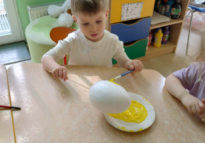 Chłopiec koloruje styropianowe jajko