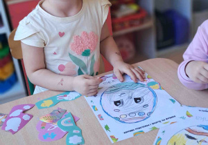 Dzieci przy stoliku ozdabiają kredkami i naklejkami wielkanocne pisanki