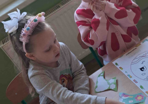 Dzieci przy stoliku ozdabiają kredkami i naklejkami wielkanocne pisanki