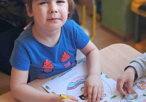 Dzieci przy stoliku ozdabiają kredkami i naklejkami wielkanocne pisanki