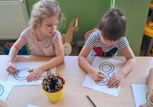 Dzieci przy stoliku kolorują znak nieskończoności