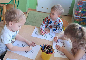 Dzieci przy stoliku kolorują znak nieskończoności