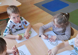 Dzieci przy stoliku kolorują znak nieskończoności