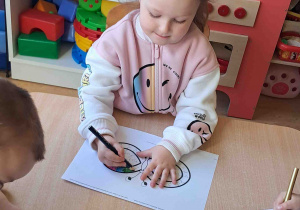 Dzieci przy stoliku kolorują znak nieskończoności