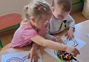 Dzieci przy stoliku kolorują znak nieskończoności