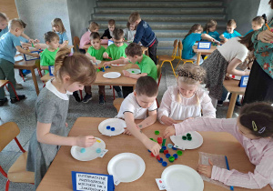 Dzieci wykonują zadania przy stoliczkach