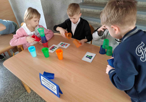 Dzieci układają konstrukcje z kolorowych kubeczków