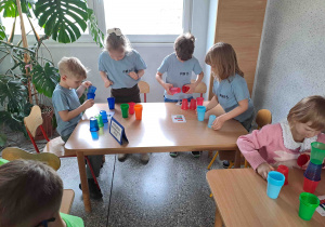 Dzieci układają konstrukcje z kolorowych kubeczków