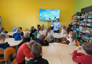 Dzieci w bibliotece oglądają prezentację na temat zwiastunów wiosny