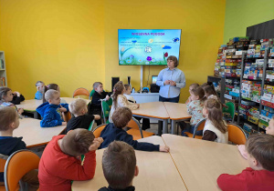 Dzieci w bibliotece oglądają prezentację na temat zwiastunów wiosny