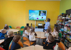 Dzieci w bibliotece oglądają prezentację na temat zwiastunów wiosny