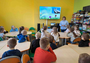 Dzieci w bibliotece oglądają prezentację na temat zwiastunów wiosny