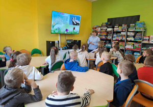 Dzieci w bibliotece oglądają prezentację na temat zwiastunów wiosny