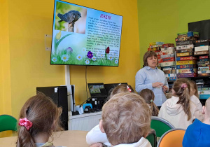 Dzieci w bibliotece oglądają prezentację na temat zwiastunów wiosny