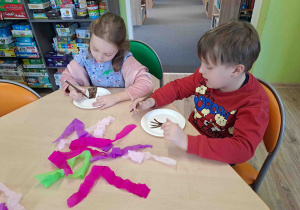 Dzieci wykonują pracę plastyczną "Kwitnące drzewko" z wykorzystaniem talerzyków papierowych i kolorowej bibuły