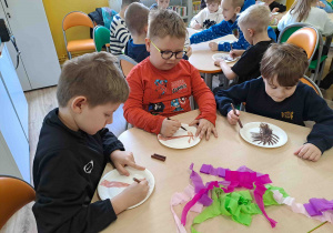 Dzieci wykonują pracę plastyczną "Kwitnące drzewko" z wykorzystaniem talerzyków papierowych i kolorowej bibuły
