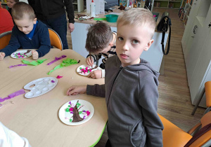 Dzieci wykonują pracę plastyczną "Kwitnące drzewko" z wykorzystaniem talerzyków papierowych i kolorowej bibuły
