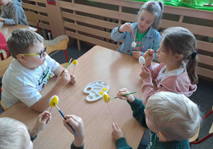 Dzieci malują na żółto styropianowe jajeczka