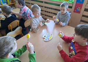 Dzieci malują na żółto styropianowe jajeczka