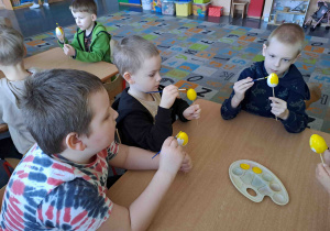 Dzieci malują na żółto styropianowe jajeczka