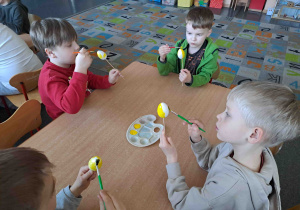 Dzieci malują na żółto styropianowe jajeczka
