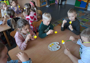 Dzieci malują na żółto styropianowe jajeczka