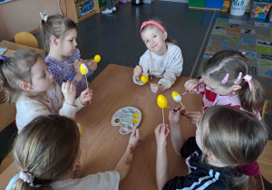 Dzieci malują na żółto styropianowe jajeczka