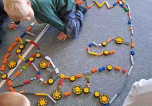 Dzieci układają na podłodze pisanki - giganty z klocków