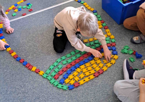 Dzieci układają na podłodze pisanki - giganty z klocków