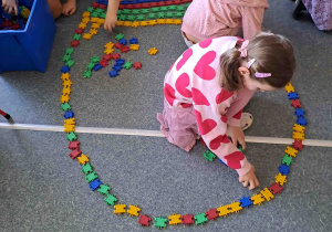 Dzieci układają na podłodze pisanki - giganty z klocków