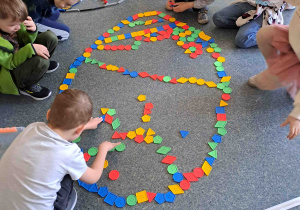 Dzieci układają na podłodze pisanki - giganty z klocków