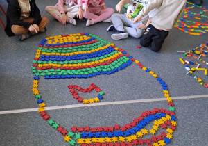 Dzieci układają na podłodze pisanki - giganty z klocków