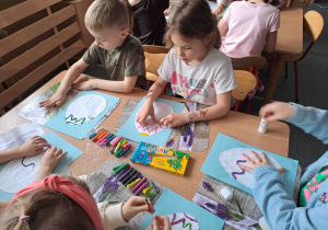 Dzieci tworzą wzorki z wałeczków plasteliny na konturach pisanek