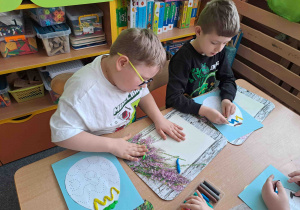 Dzieci tworzą wzorki z wałeczków plasteliny na konturach pisanek