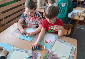 Dzieci tworzą wzorki z wałeczków plasteliny na konturach pisanek