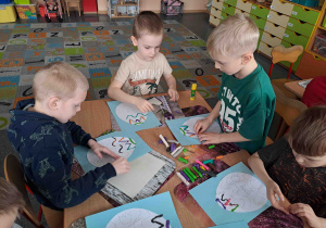 Dzieci tworzą wzorki z wałeczków plasteliny na konturach pisanek