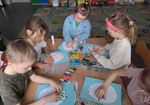 Dzieci tworzą wzorki z wałeczków plasteliny na konturach pisanek