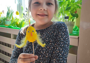 Dzieci wykonują kurczątka z wcześniej pomalowanych jajeczek, piórek i pianki plastycznej