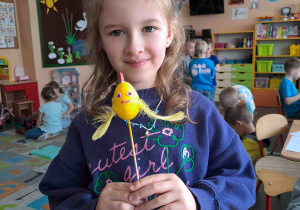 Dzieci wykonują kurczątka z wcześniej pomalowanych jajeczek, piórek i pianki plastycznej