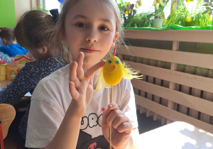 Dzieci wykonują kurczątka z wcześniej pomalowanych jajeczek, piórek i pianki plastycznej