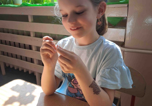 Dzieci wykonują kurczątka z wcześniej pomalowanych jajeczek, piórek i pianki plastycznej