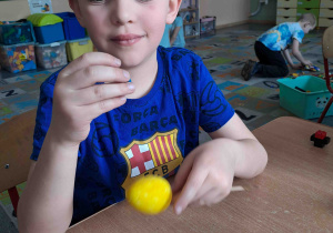 Dzieci wykonują kurczątka z wcześniej pomalowanych jajeczek, piórek i pianki plastycznej