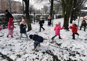Siedmioro dzieci biega po śniegu.