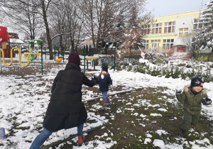 Nauczycielka bawi się z chłopcem rzucają się śnieżkami.