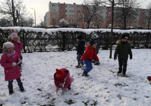 Sześcioro dzieci lepi kule aby zrobić bałwana.