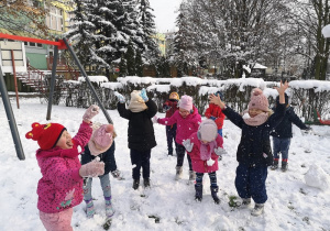 Dzieci z wesołymi minkami podskakują i porzucają śnieg do góry.