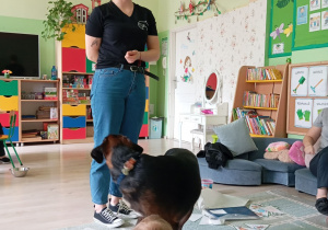 Pani w czarnej koszulce pokazuje sztuczkę z psem