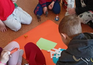 Dzieci przyklejają elementy na makietę