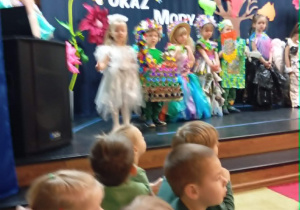 Dzieci stoją na scenie w strojach z materiałów ekologicznych